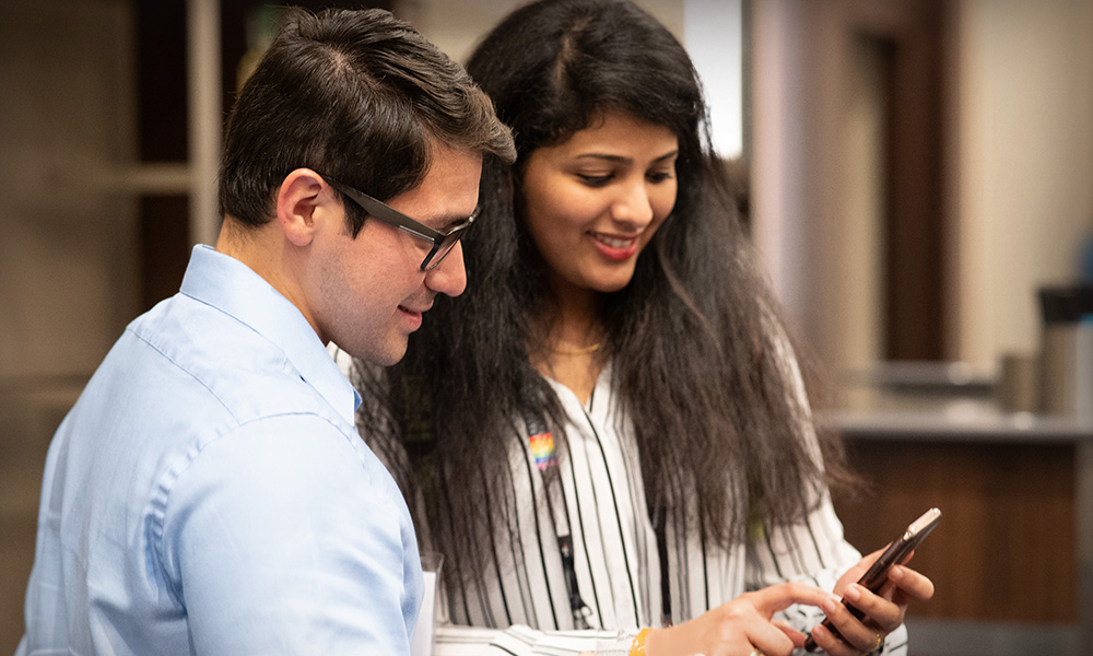 Two people looking at a mobile app on their phone