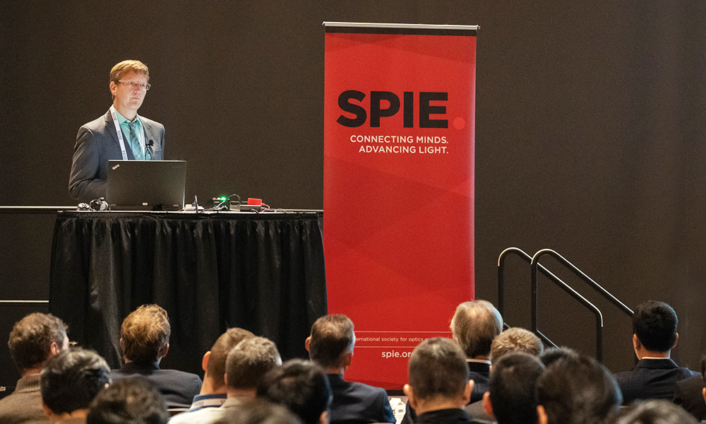 A speaker presenting research to a room full of colleagues at an SPIE conference