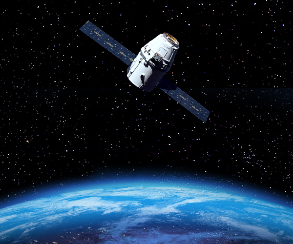 Satellite orbiting above Earth with extended solar panels, overlooking the planet’s illuminated surface against a star-filled space backdrop.